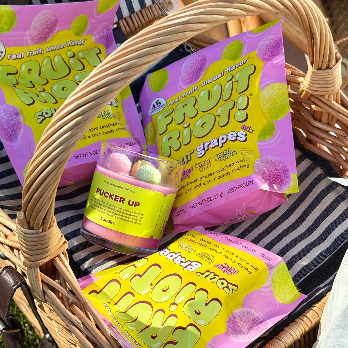 Gift basket filled with Candier Fruit Riot Sour Grapes candles and candy packaging. Pretty candles inspired by fruit riot candy and 90s aesthetic for fans of cute, food inspired scents.