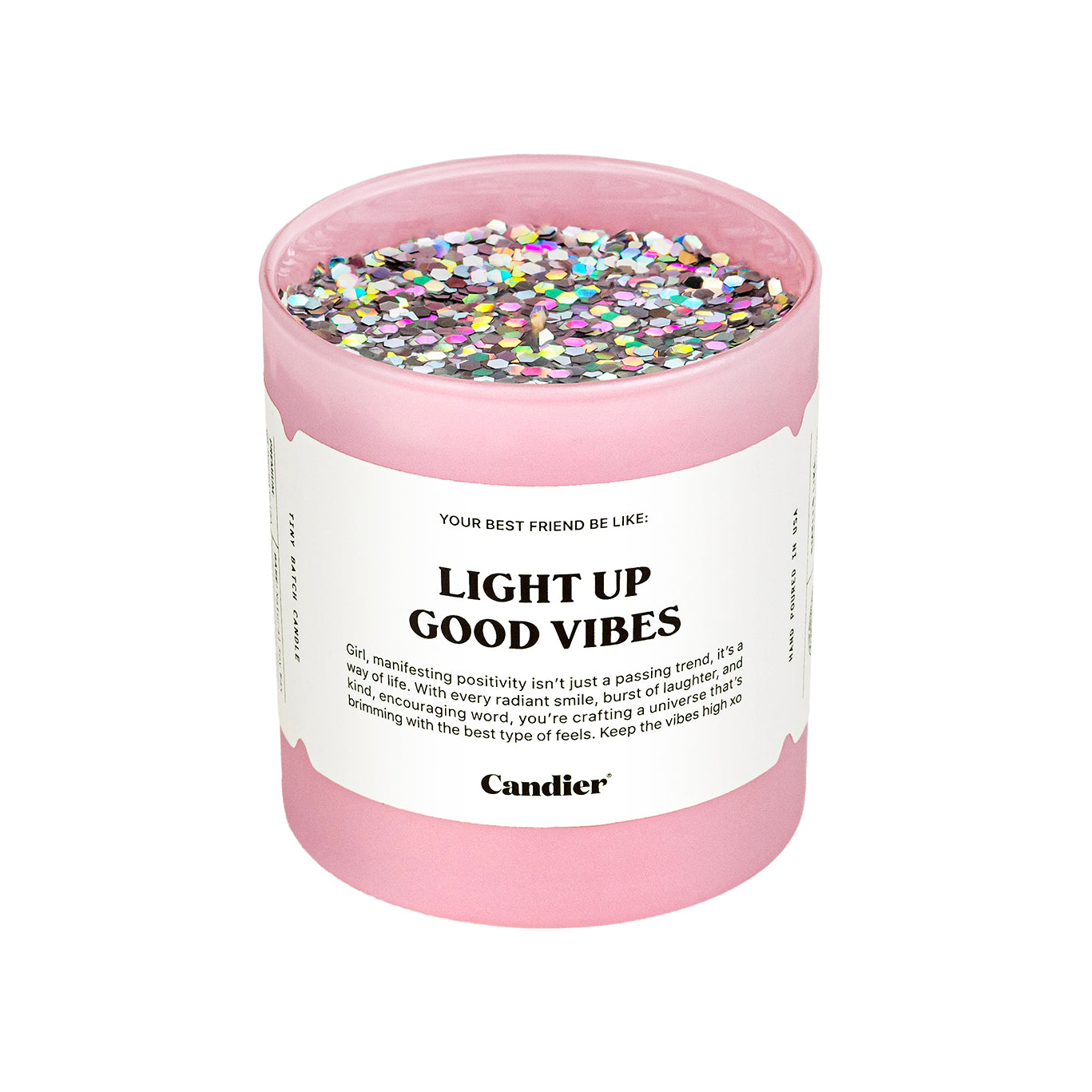 A pink candle with sparkling holographic glitter on top and a label that reads light up good vibes