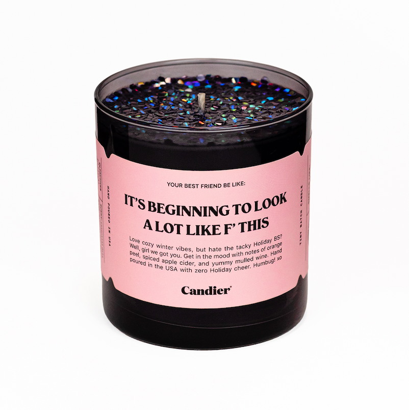 A Grinchy Christmas themed Candier candle in a glossy black glass vessel, topped with sparkling black and holographic glitter, and a light pink label that reads “It’s Beginning To Look A Lot Like Christmas”