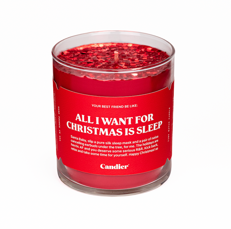 A Christmas themed Candier candle in a clear glass vessel, filled with festive red wax, topped with sparkling red glitter and a Santa red label that reads "All I Want For Christmas Is Sleep"