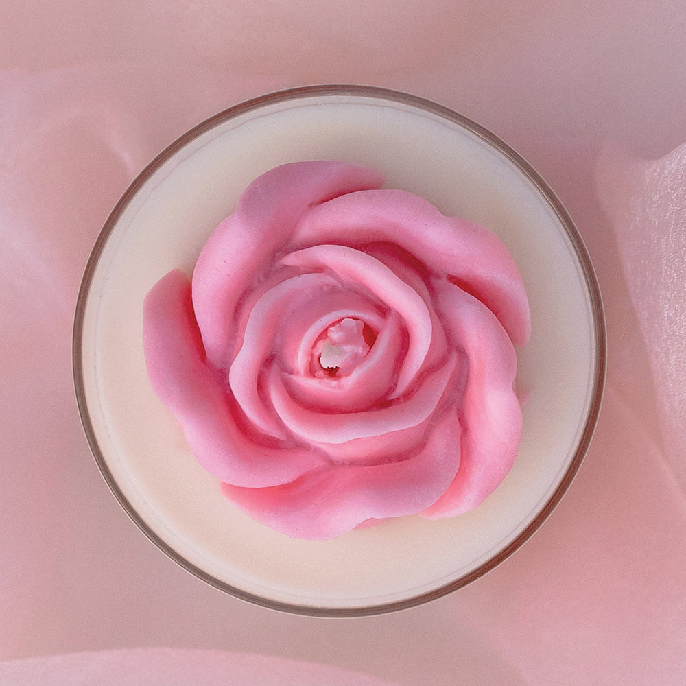 a scented candle with a sculpted rose made of wax