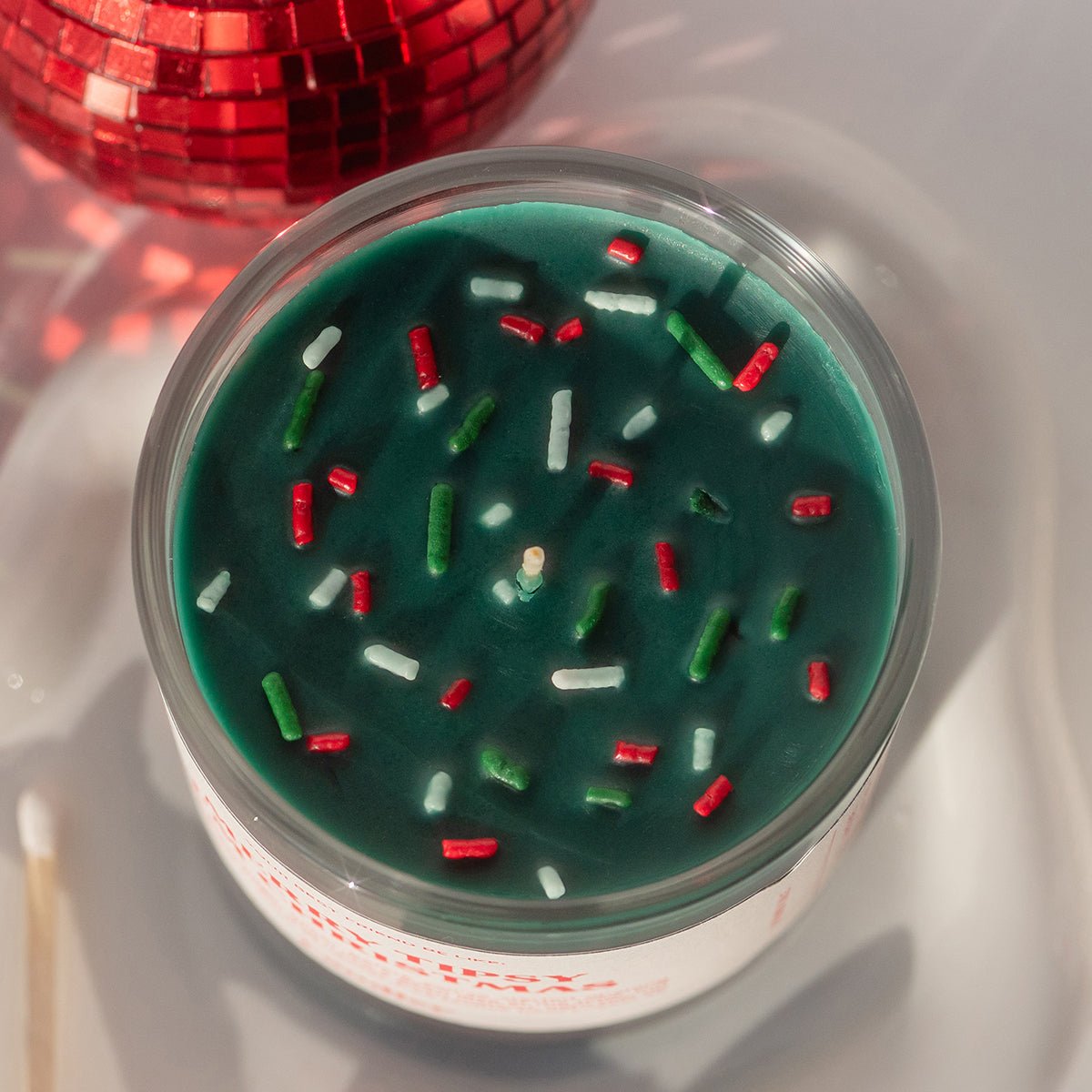 op view of Candier green Christmas scented candle with candy-cane sprinkles — classic apple cinnamon candle and best Christmas gifts for mom.