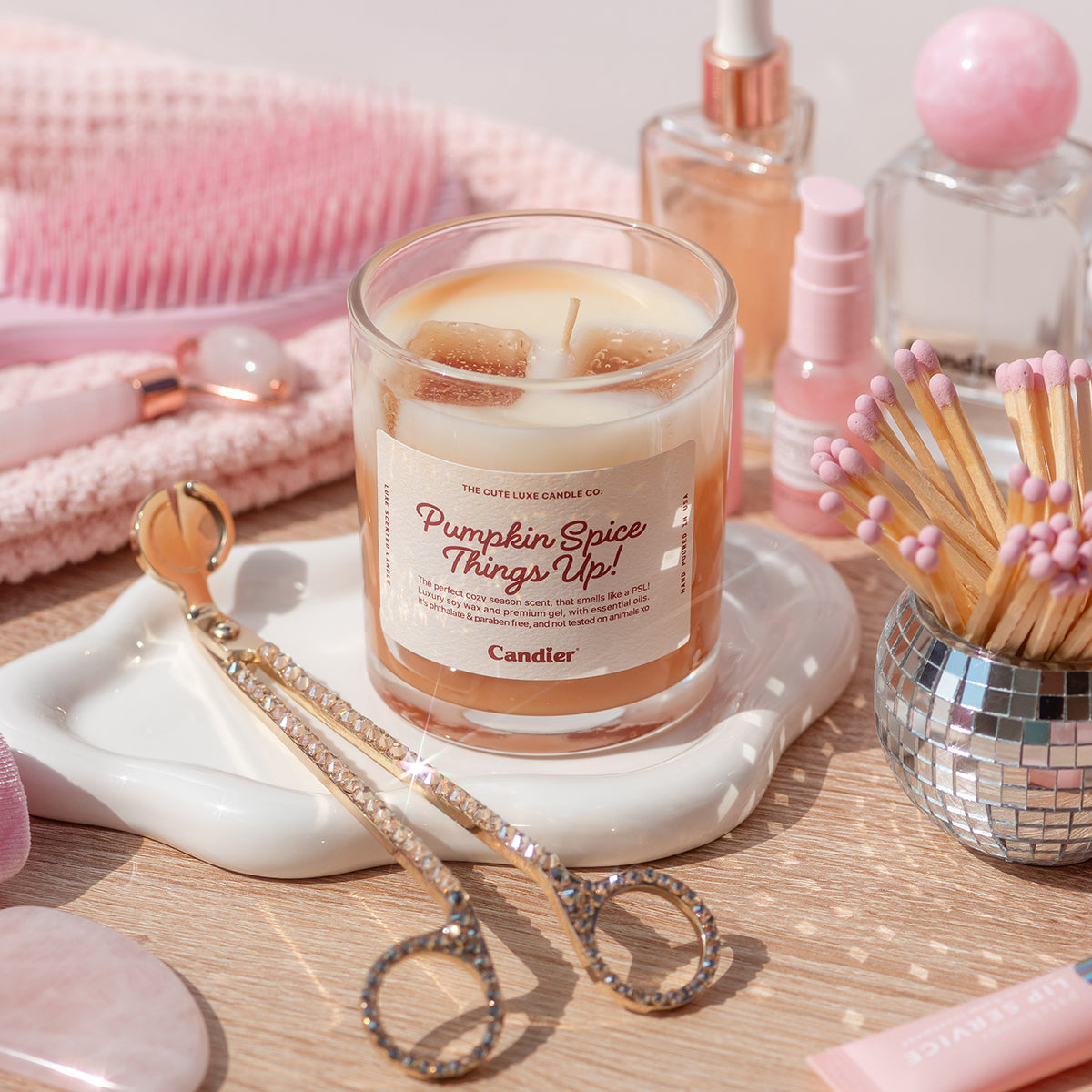 Pretty Candier pumpkin spice candle styled with beauty products, cozy aesthetic dessert candle for cute room decor and luxe gifting.