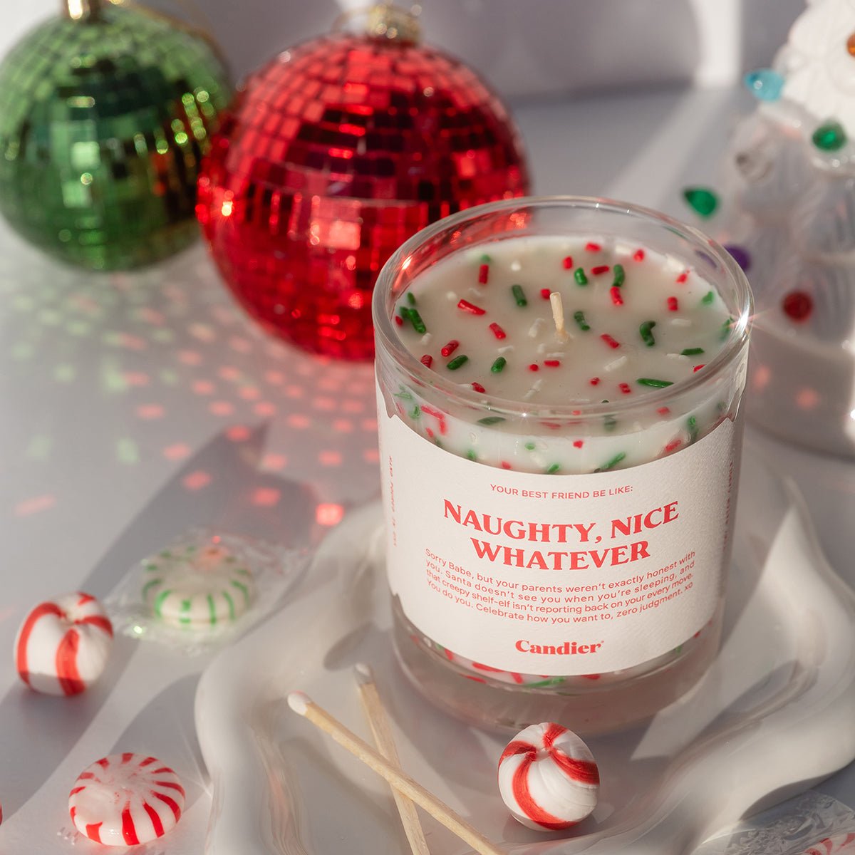 Pretty Christmas candle on gift wrap—cute aesthetic lux candle; best Secret Santa gifts and white elephant gift ideas $50.