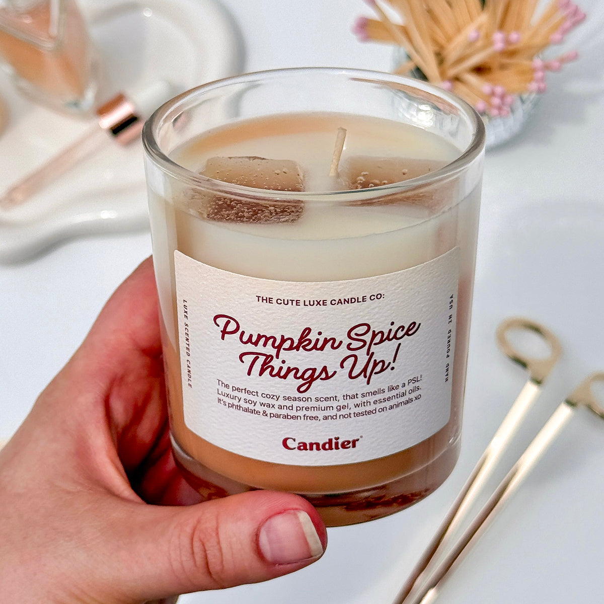 Cute pumpkin latte candle by Candier held in hand, cozy aesthetic fall candle perfect for cute gifts for friends and young women.