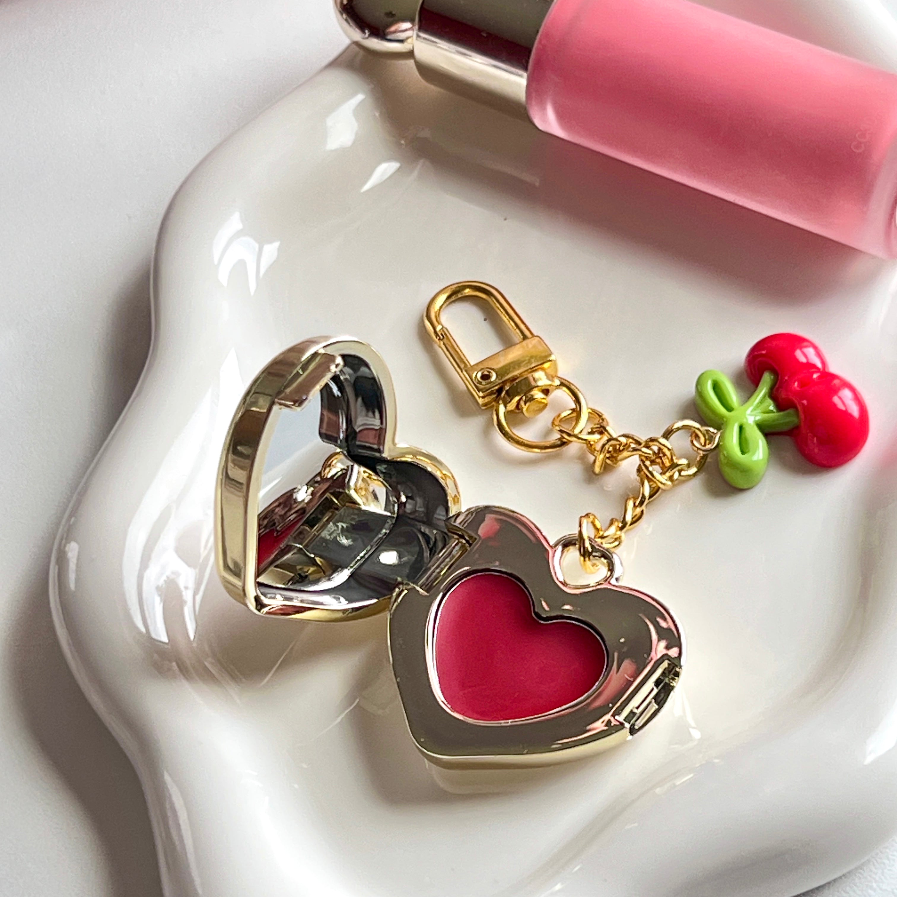 Open gold heart lip balm keychain on ceramic tray â 90's aesthetic compact mirror locket with red tint balm and cherry charm