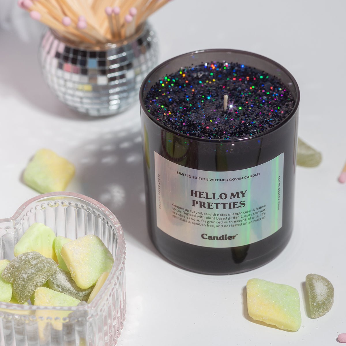 CandierĀ® Hello My Pretties candle styled with green treats and glitter wax, a wickedly glam Wizard of Oz inspired Halloween candle for luxe aesthetic lovers.