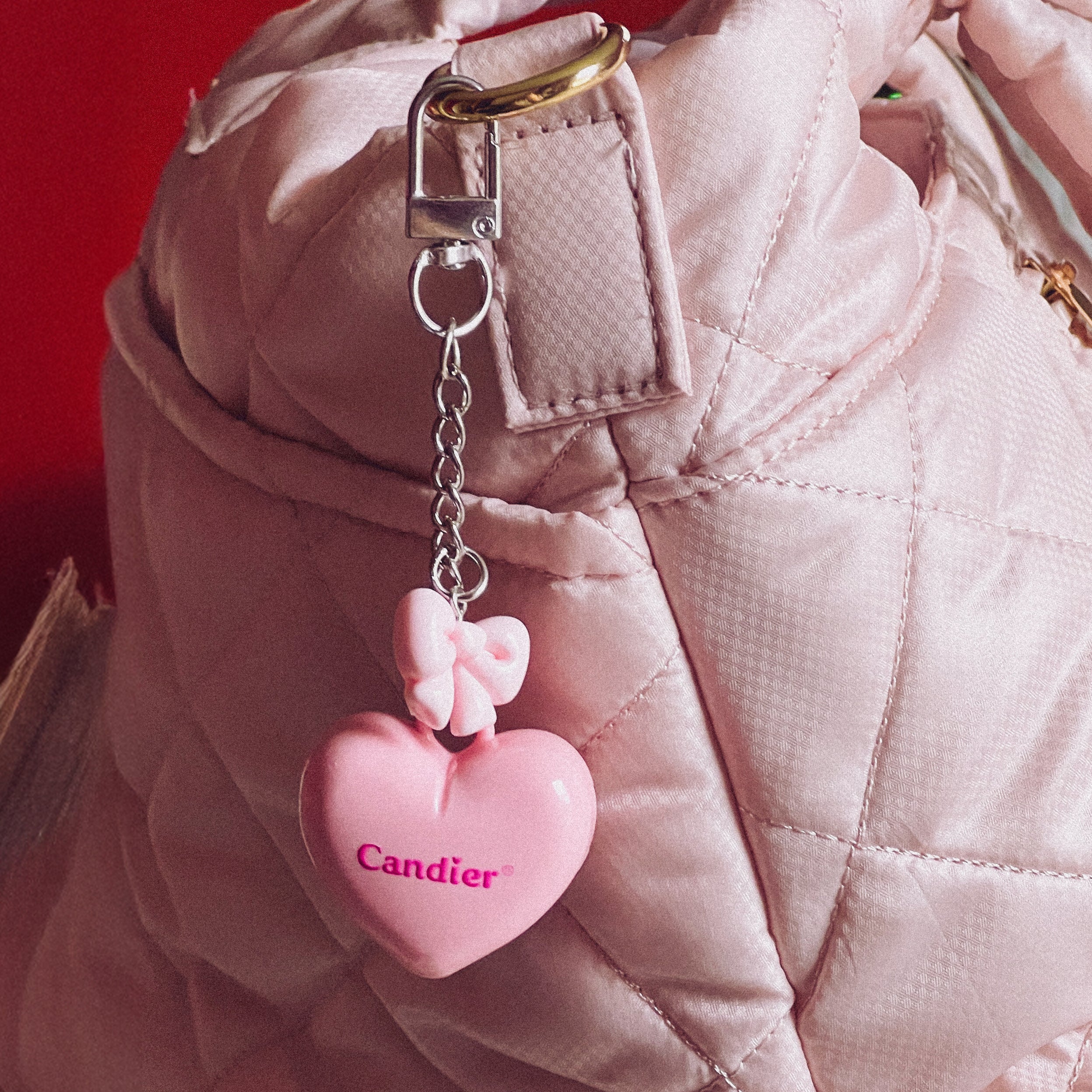 Pink heart lip balm locket clipped to quilted backpack – cute keychain for girls and teens