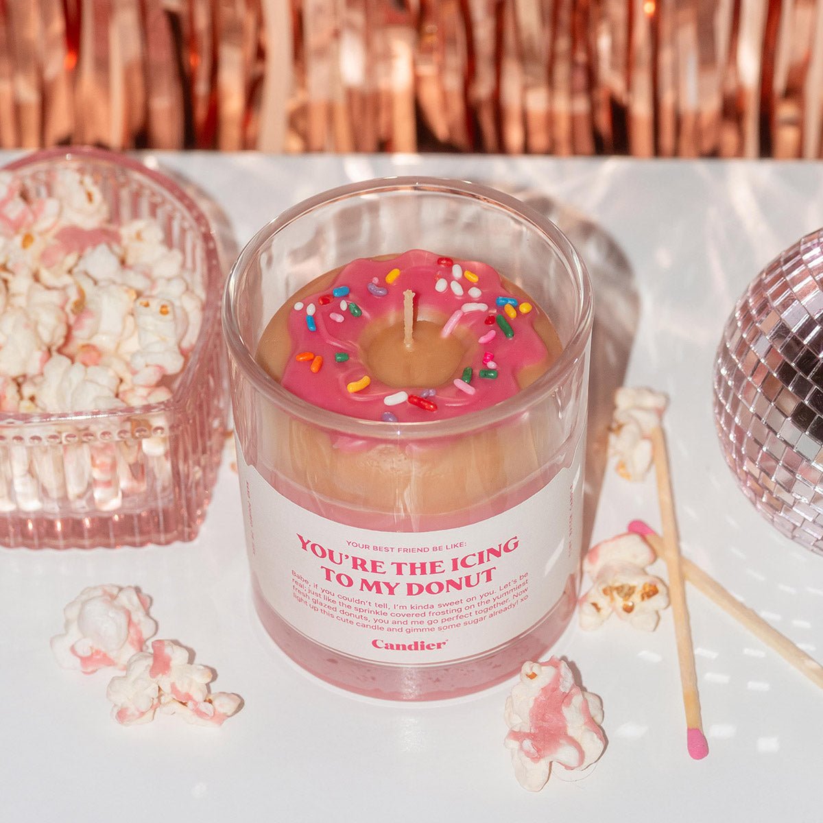 Candier You’re the Icing to My Donut dessert candle featuring a realistic strawberry glazed donut wax topper with sprinkles, styled with popcorn, pink matches, and romantic Valentine’s Day decor