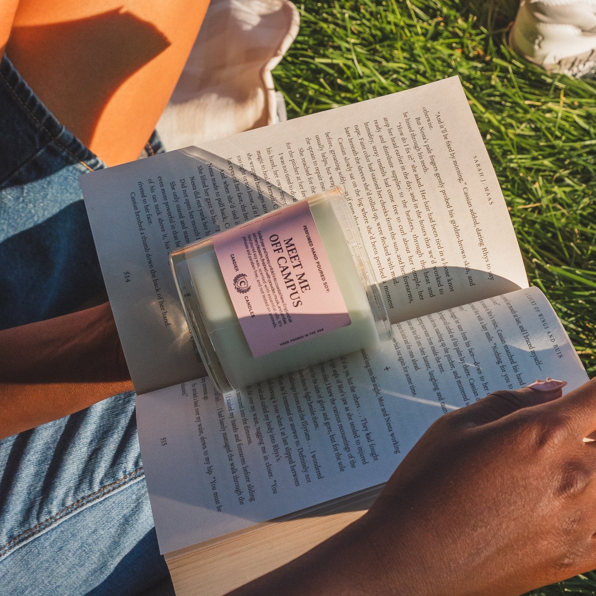 Meet Me Off Campus candle styled with an open book outdoors, a cute gift for college girls and students