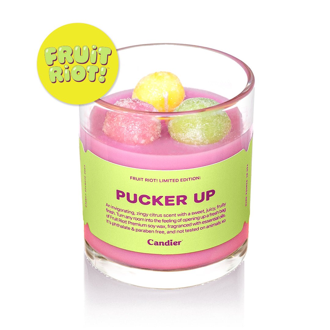 Candier Fruit Riot candle “Pucker Up” with bright pink wax, citrus candy-inspired topping, and bold neon label. A cute, food-scented dessert candle with candycore, citrus scent vibes and Y2K aesthetic.
