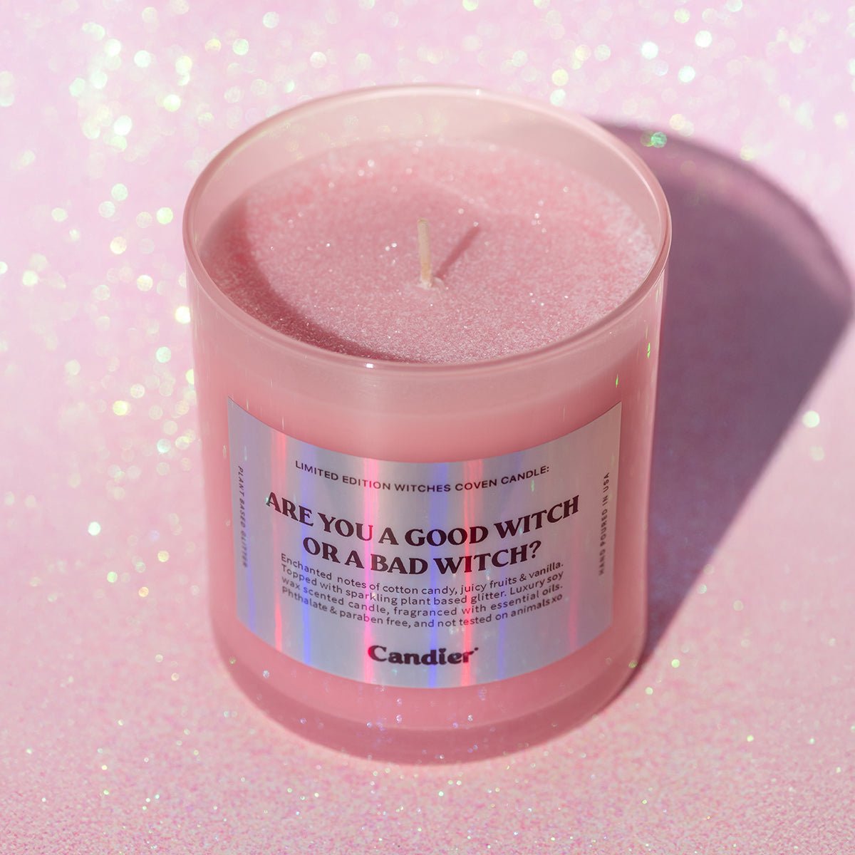 CandierĀ® Are You a Good Witch or a Bad Witch candle on pink glitter background, a luxe and pretty Halloween candle that makes a perfect gift for a young woman.