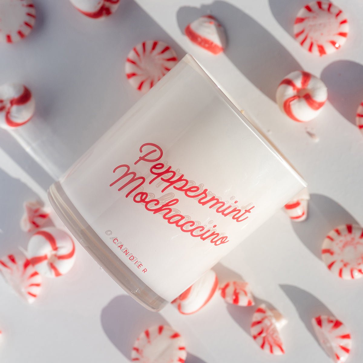 Flatlay of peppermint mocha candle with candy canes—cozy Christmas candles; steal-worthy white elephant gift ideas $50.