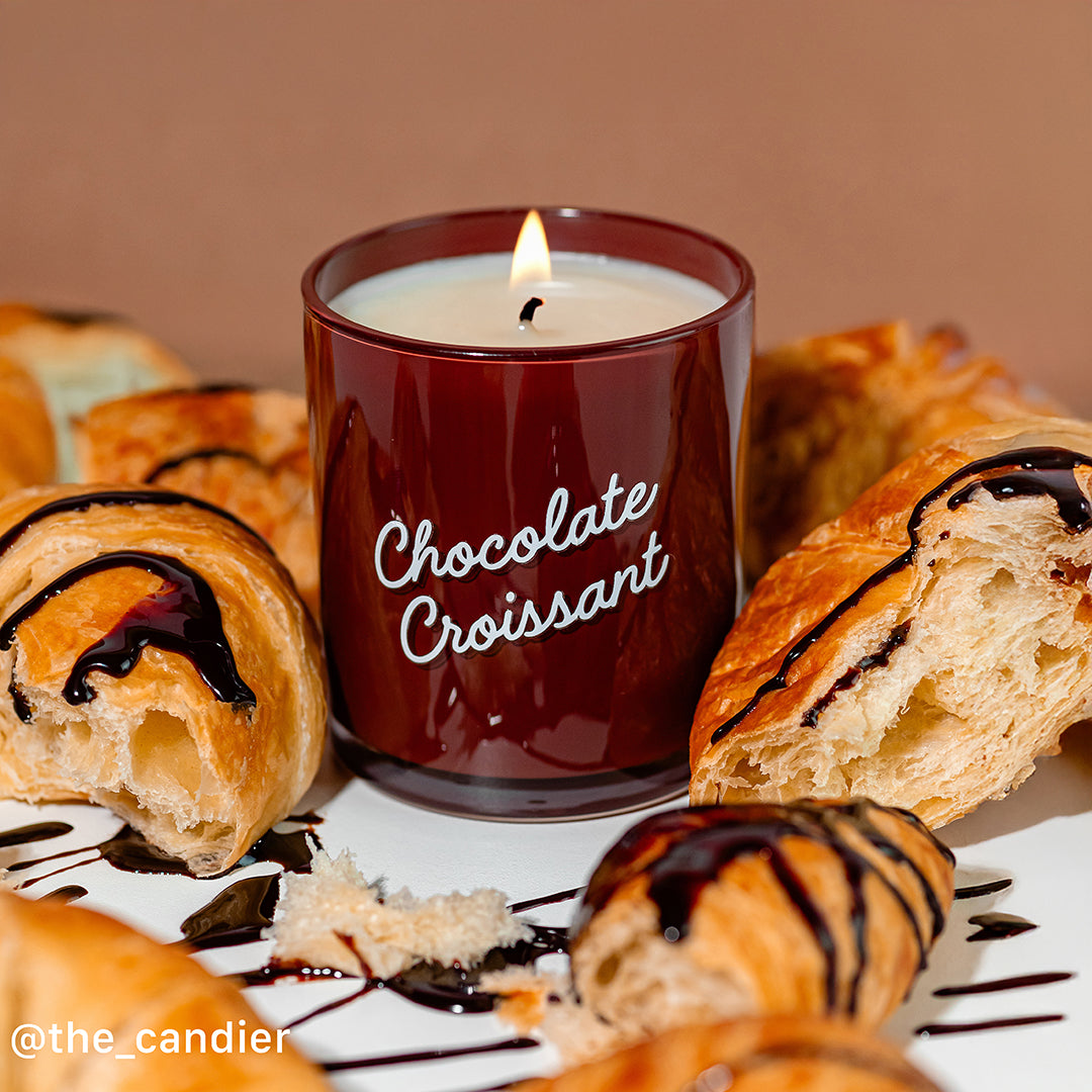 Candier Chocolate Croissant candle styled with flaky pastries and chocolate drizzle. A food-scented candle with gourmand fragrance and warm and cozy aesthetic food vibes.
