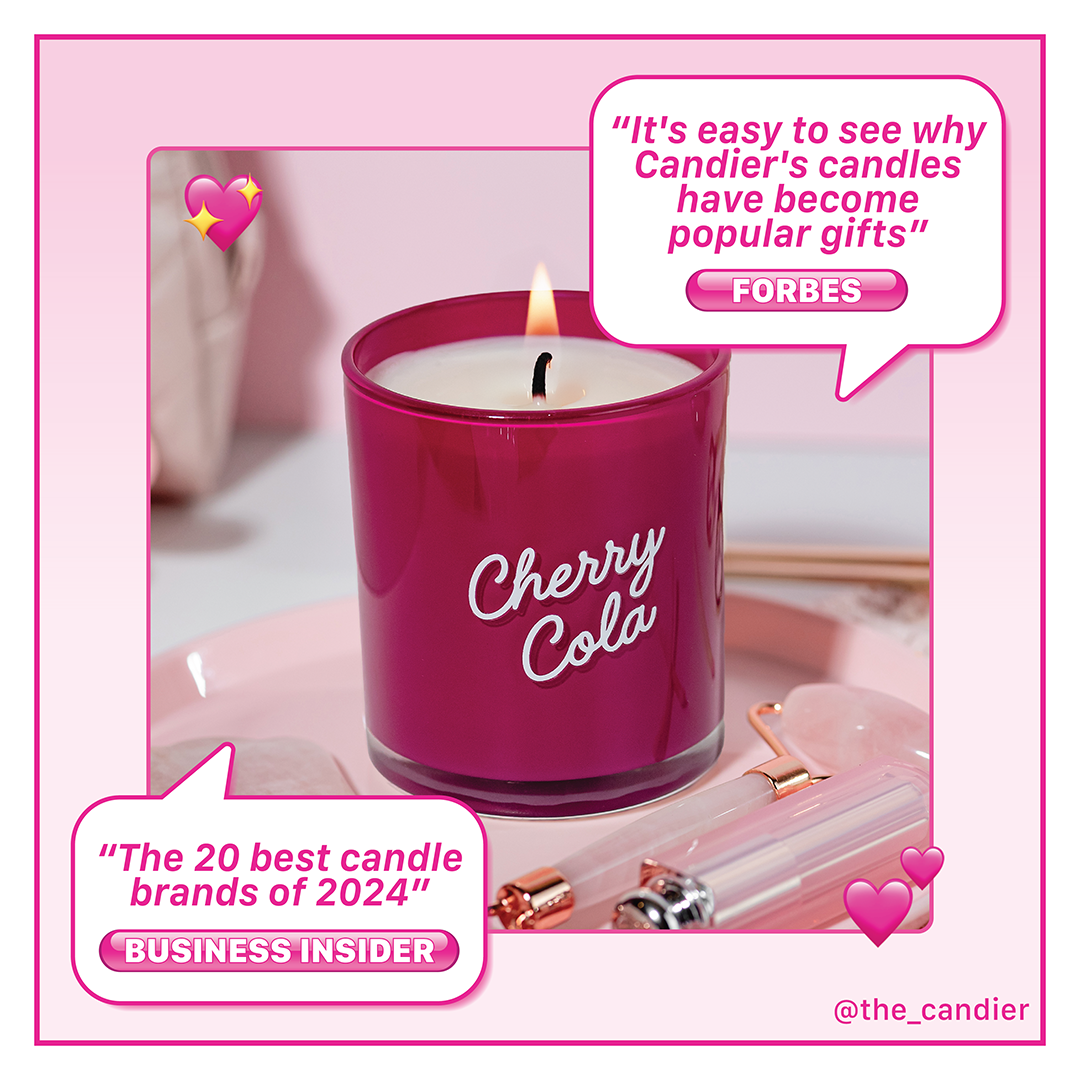 Cherry Cola scented candle by Candier, styled on a pink vanity tray with rose quartz and lip gloss. Includes quotes from Forbes and Business Insider praising Candier as one of the best candle brands and most popular gift picks. Aesthetic dessert candle with cherry vanilla and amaretto fragrance.