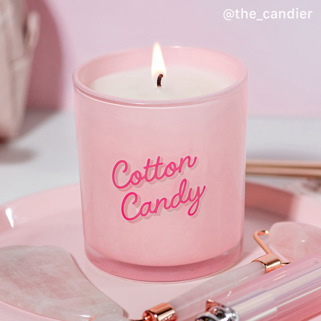 Candier candle Cotton Candy lit on a soft pink soft girl aesthetic vanity. This pink cotton candy candle blends sugar, berries, and vanilla scent for the ultimate pink aesthetic.