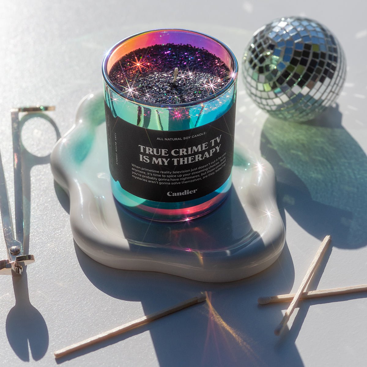 Candier Halloween Candle with 'True Crime TV is my Therapy' text on a decorative stand with disco ball and matches.