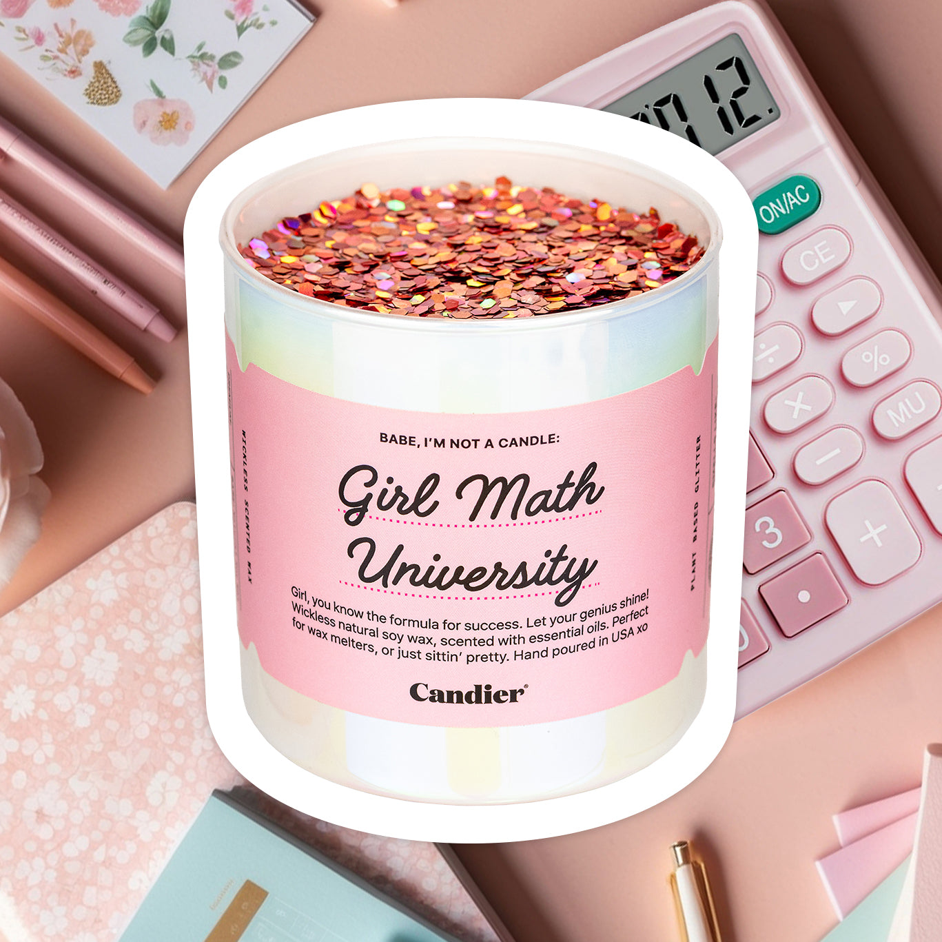 A sparkling pearl wickless candle topped with pink plant based glitter, and a label that reads Gorl Math University, by Candier, with a background of a cute desk with pink pens and a calculator