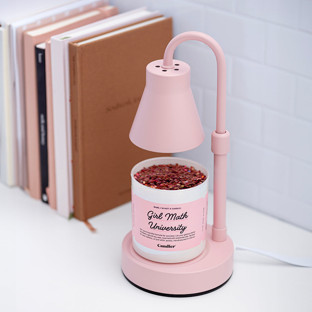 A cute pearl and pink wickless wax melt, with plant based glitter, sitting under a pink wax melter lamp and a label that reads Girl Math University, Dormables by CANDIER