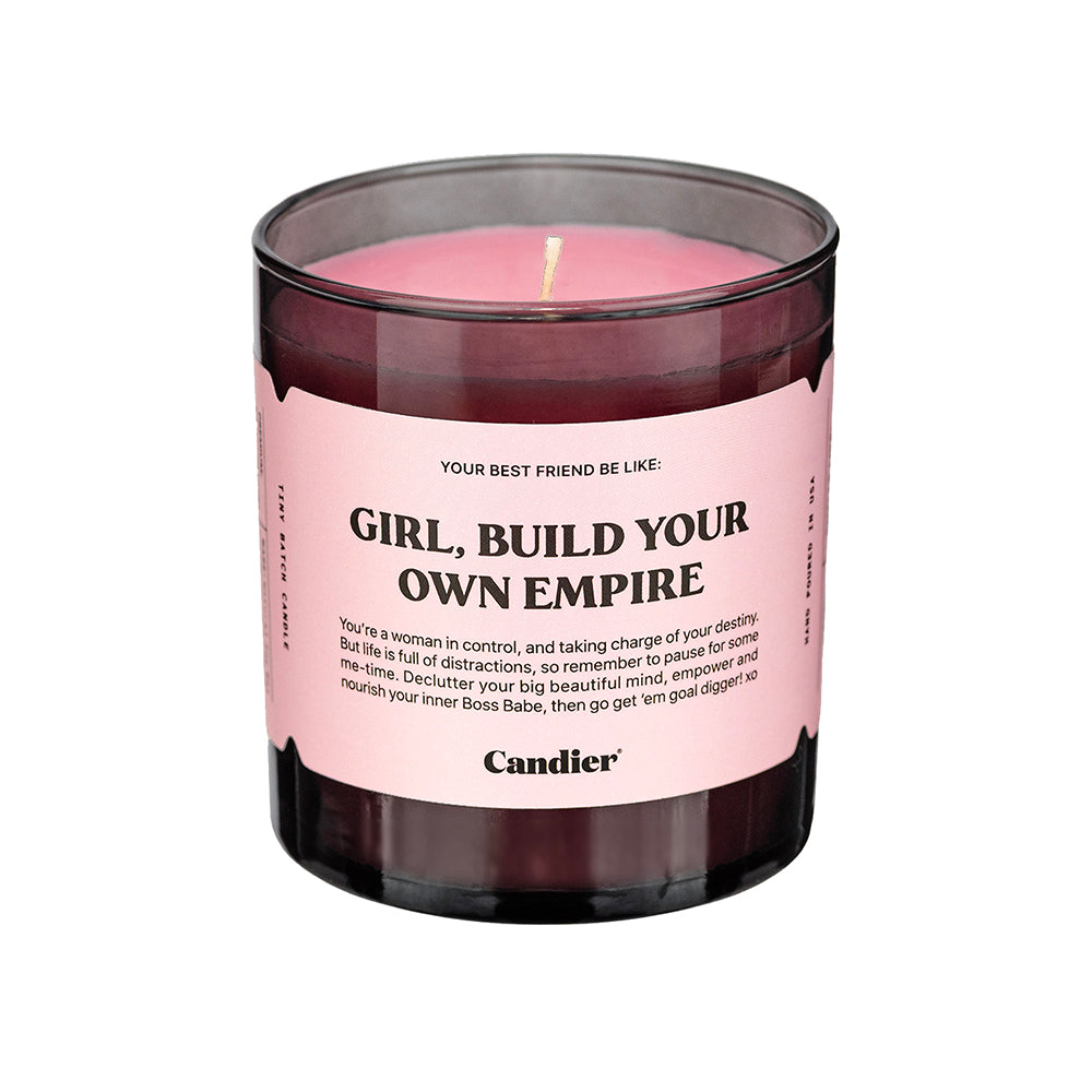 A black glass candle with a pink label that reads Girl Build Your Own Empire