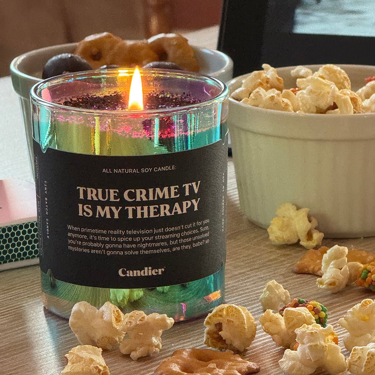 Candier Halloween Candle labeled 'True Crime TV is My Therapy' with popcorn and snacks on a table