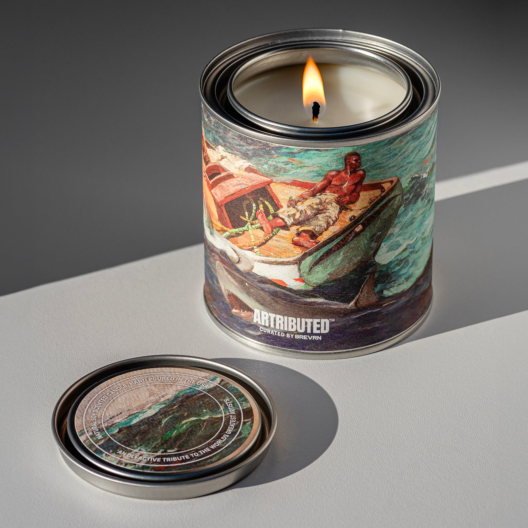 A lit fine art candle wrapped in the artwork The Gulf Stream by Winslow Homer 
