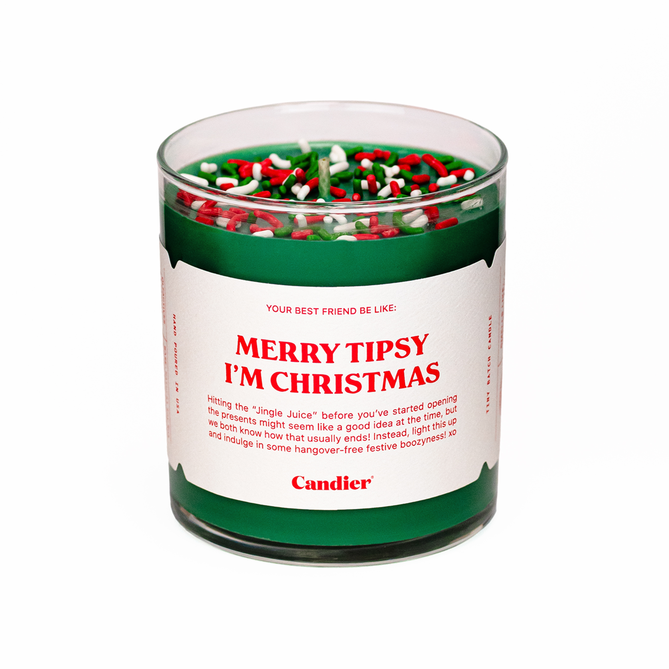 A Christmas themed Candier candle in a clear glass vessel, filled with festive green wax, topped with red, green and white sprinkles, and a white label that reads “Merry tipsy, I’m Christmas”