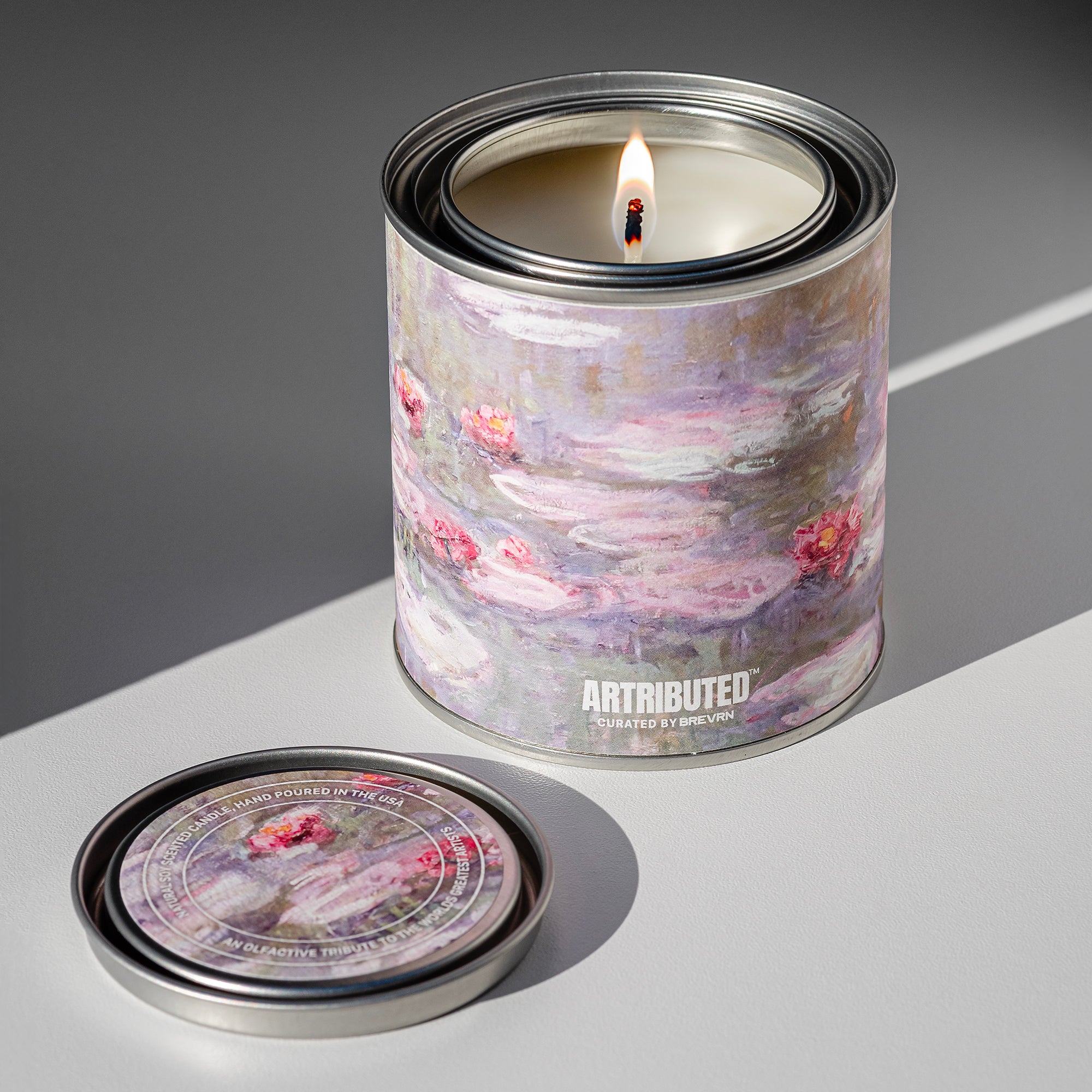 A lit candle featuring the artwork Water Lilies by Claude Monet