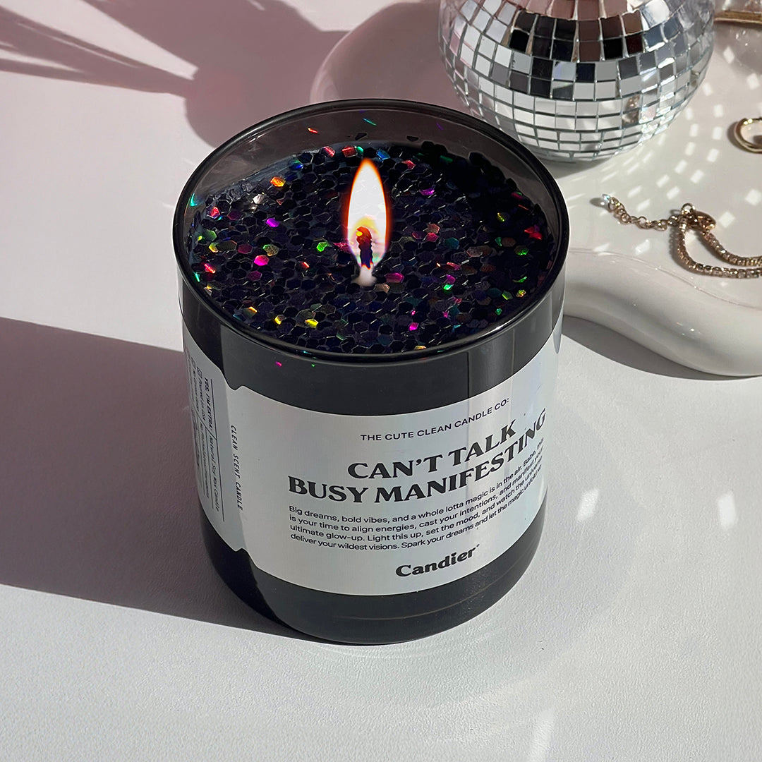 Candier cinnamon candle with holographic label beside a mini disco ball. A unique gift for women with best candle brand vibes and a mystical scent.