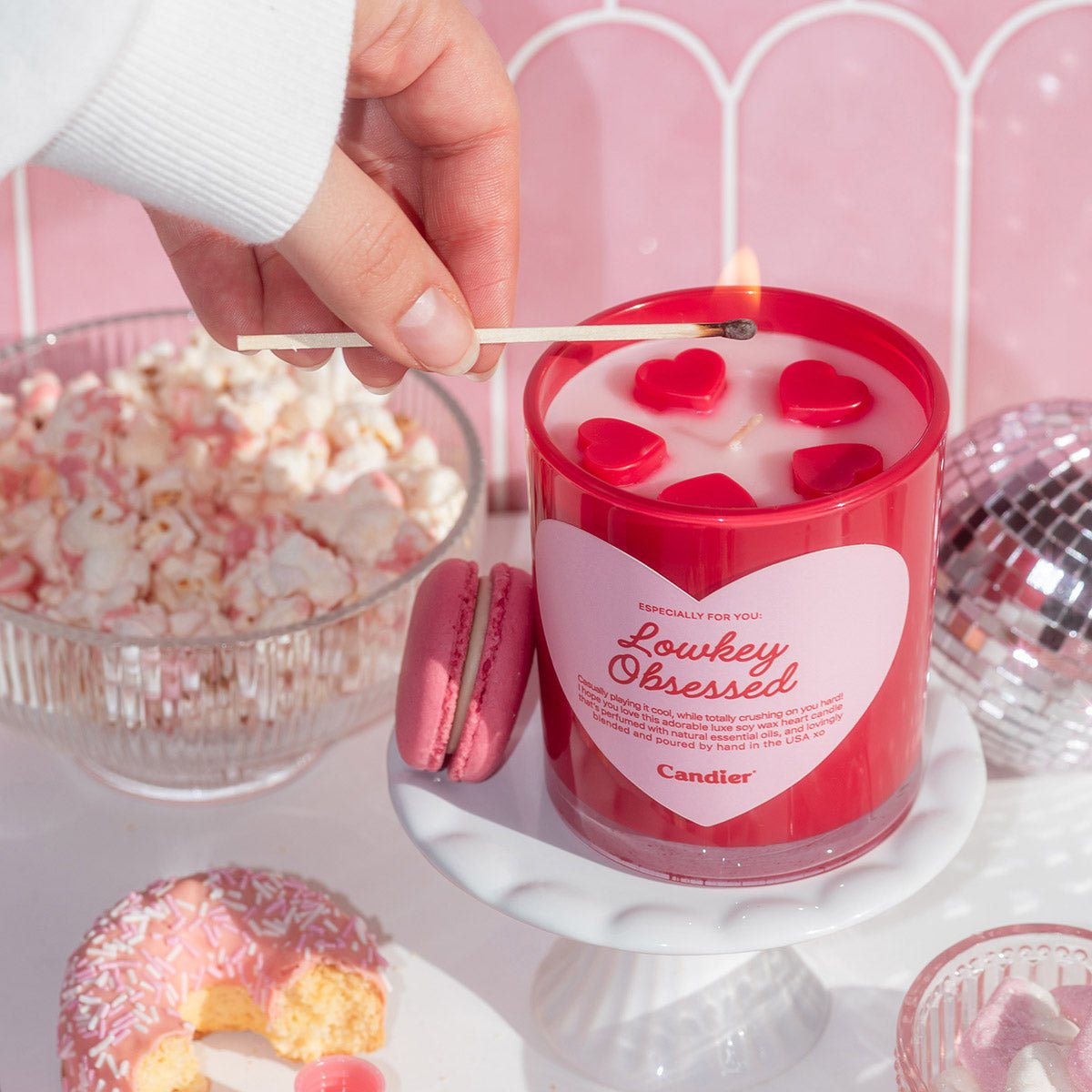 Hand holding Candier Lowkey Obsessed Valentine candle with molded wax hearts, a fruity gourmand candle and cute gift for her