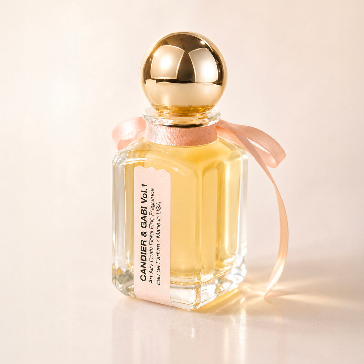Side view of Candier Pink Air perfume showing its label, pink satin bow and round gold cap.