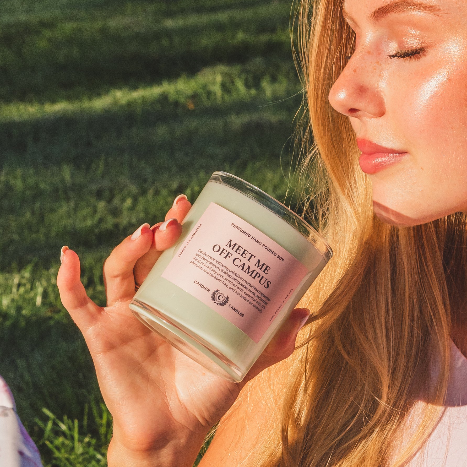 College girl holding Meet Me Off Campus candle, a unique gift for college students and sorority sisters