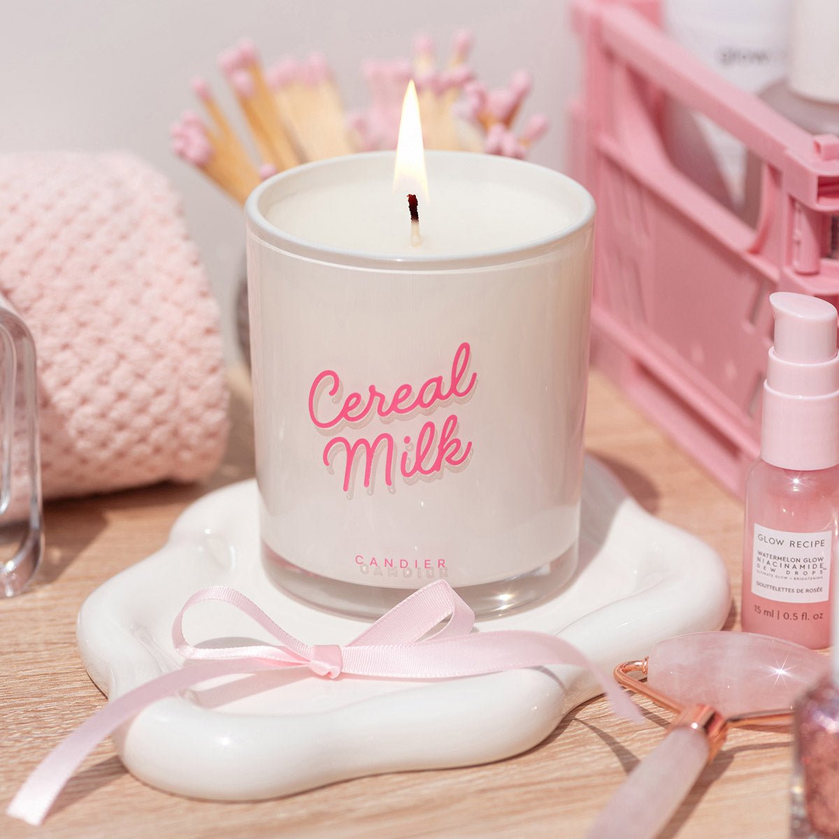 A pretty cereal candle styled in a pink aesthetic flatlay. Candier Cereal Milk Candle adds soft girl era energy to cute gifts for friends and cute room decor.